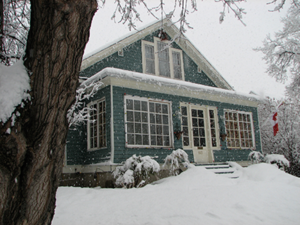 Snowy blue house with gabled roof and dormer.