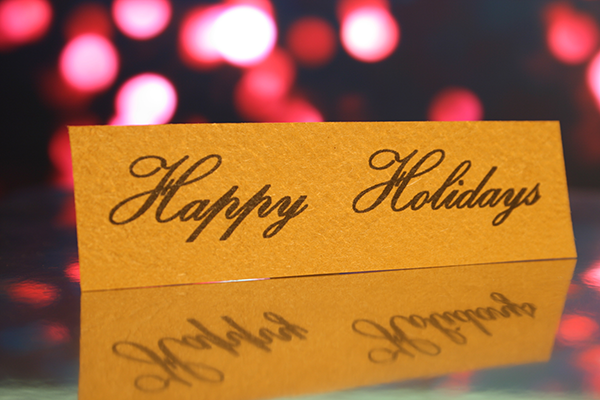 Gold card saying "Happy Holidays" on reflective surface.