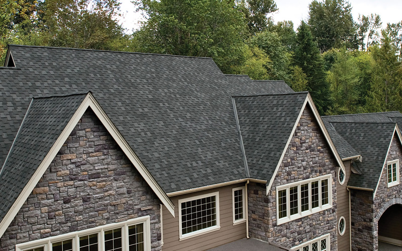 A gray asphalt roof with a multi-gabled roof on a house.