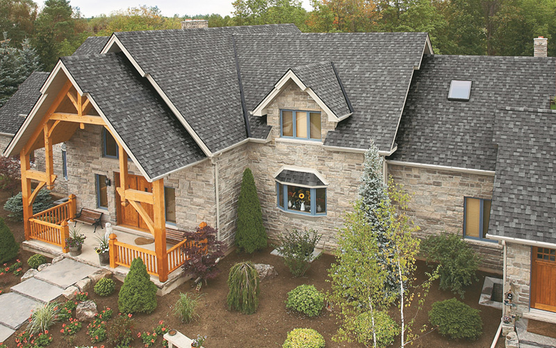 A large house with grey shingles and a stone facade.