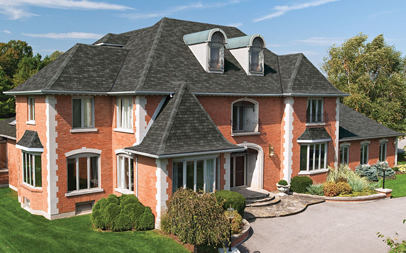 Large brick house with dark grey roof shingles.