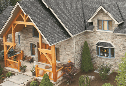 Stone house with timber porch and landscaped yard.