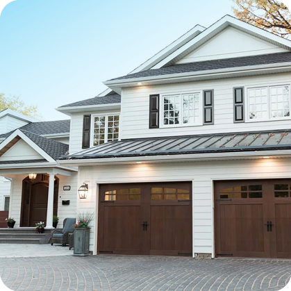 White house with wooden garage doors and metal roof.