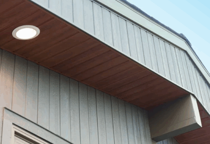Underside of a house roof with wood soffit and light.