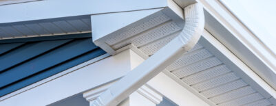Close-up of house eaves with white gutters and soffit.