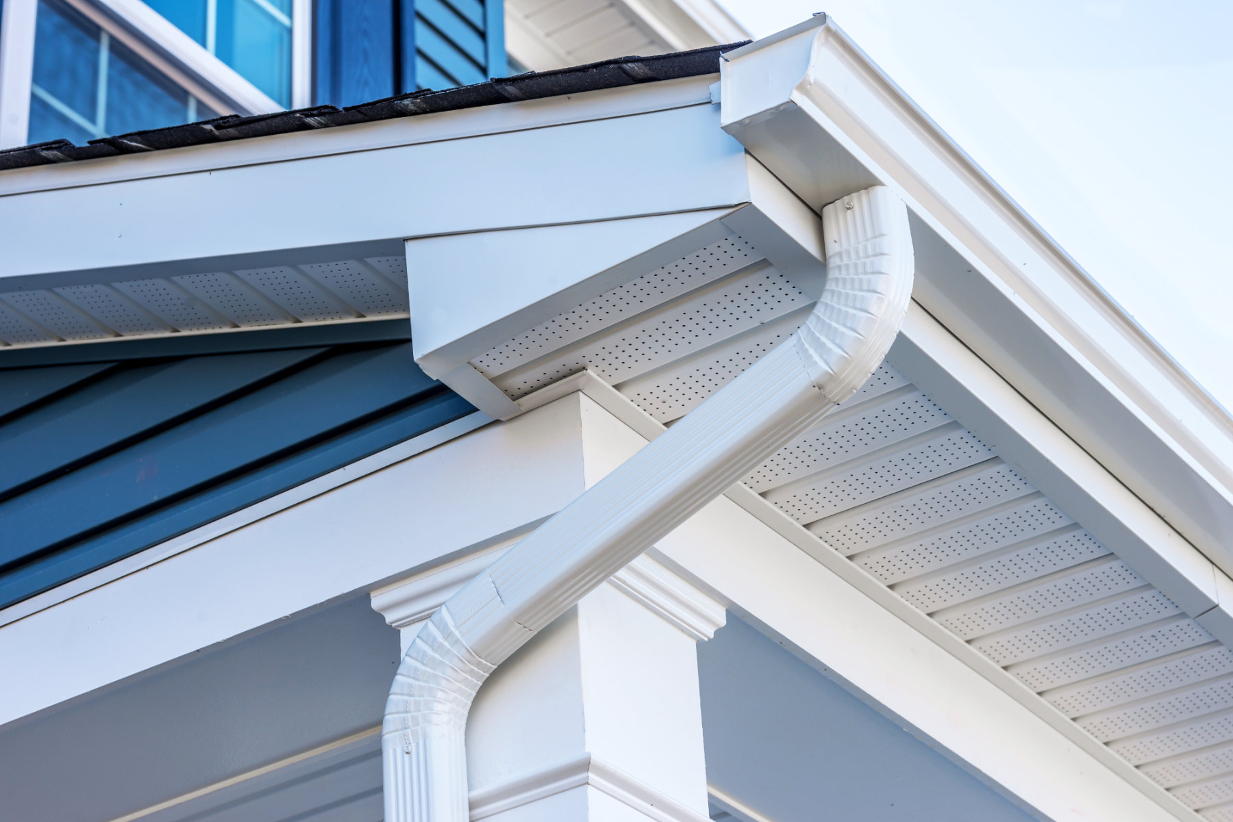 Close-up of house eaves with white gutters and soffit.