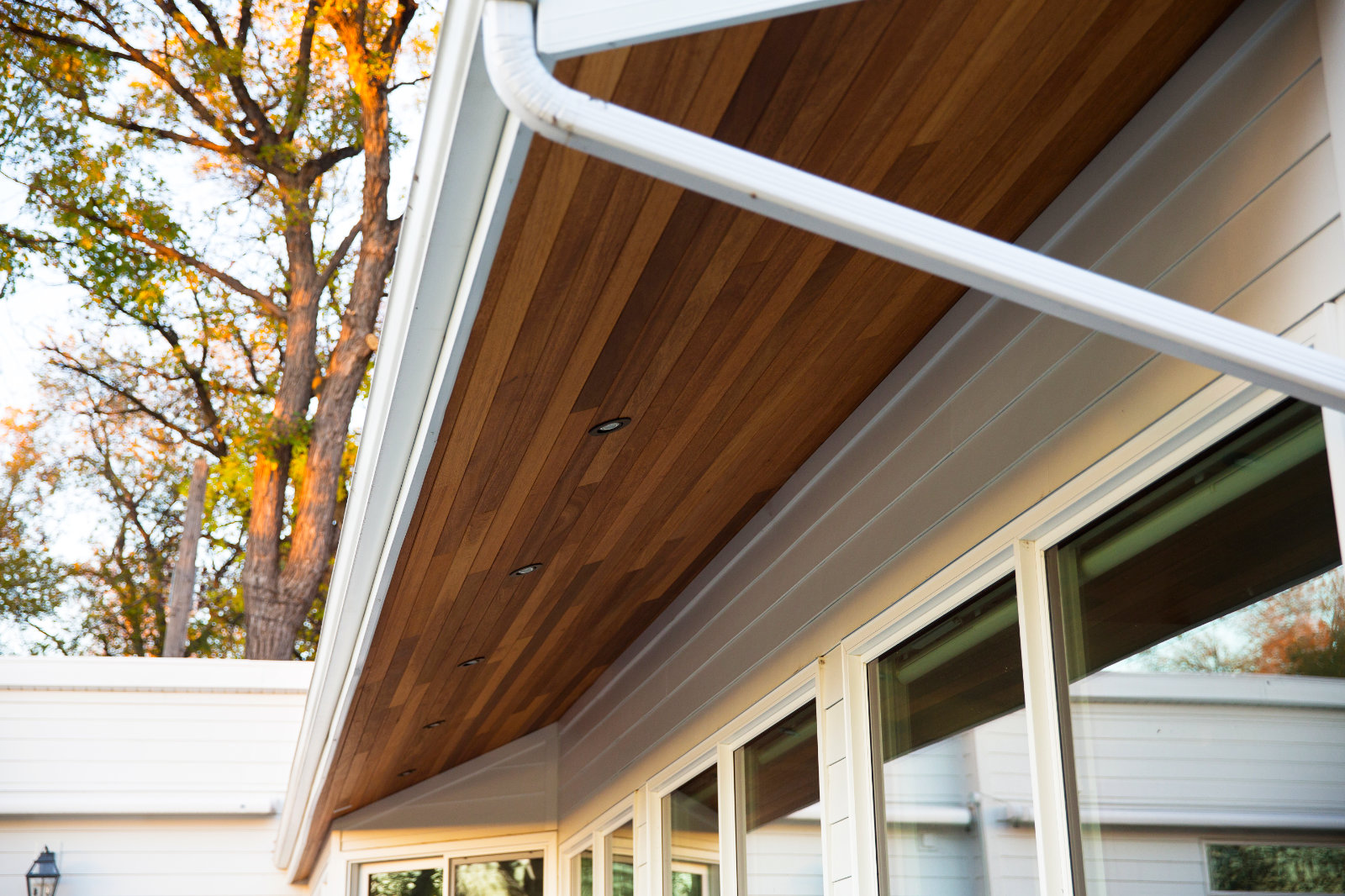 Close-up of a Winnipeg home's exterior showing natural wood soffit, white trim, and gutter above large windows.
