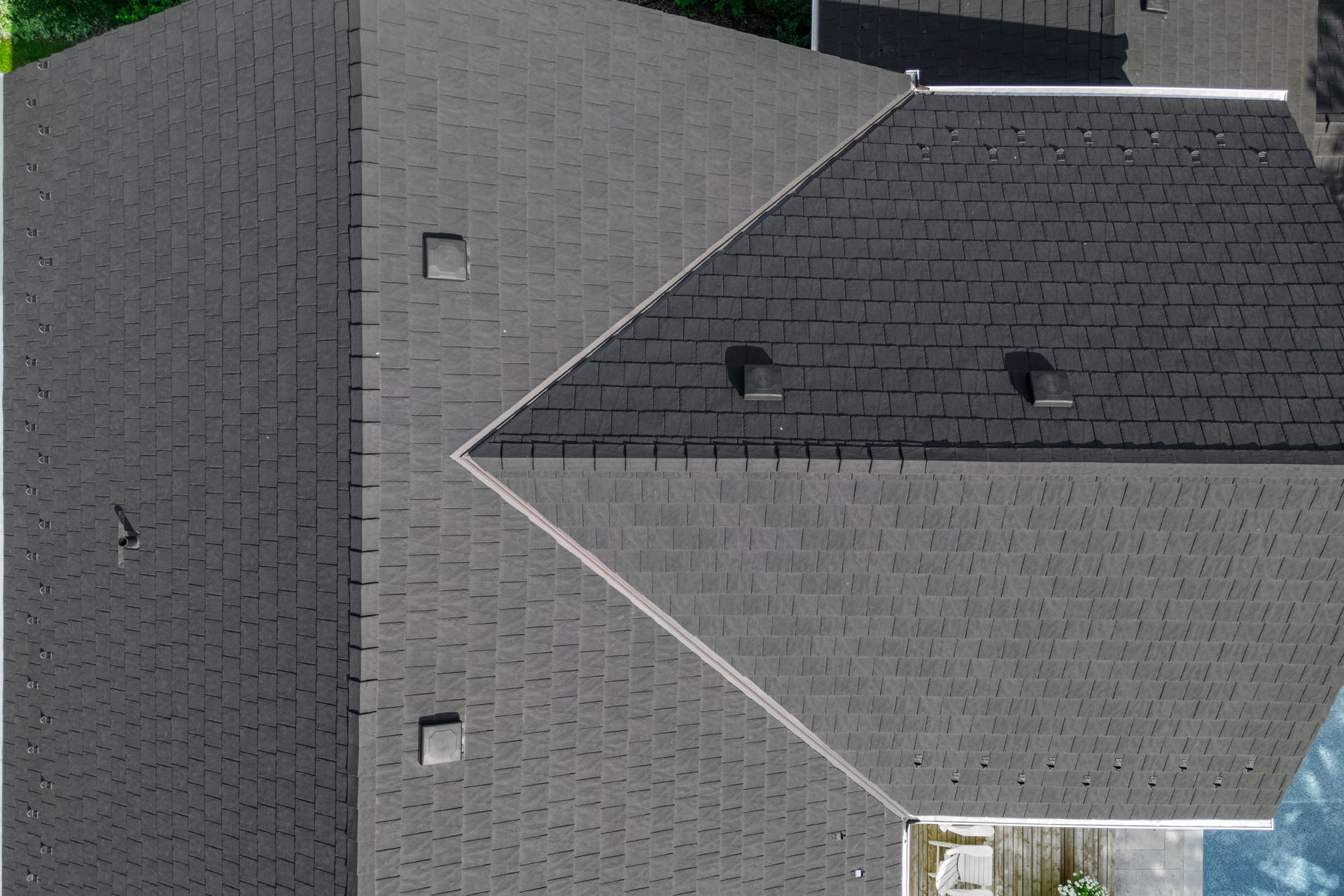 Aerial close-up of black shingle roof with vents on a residential home.